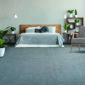 Posters Above Wooden Bed In Grey Bedroom Interior With Plants And Patterned Armchair. Real Photo